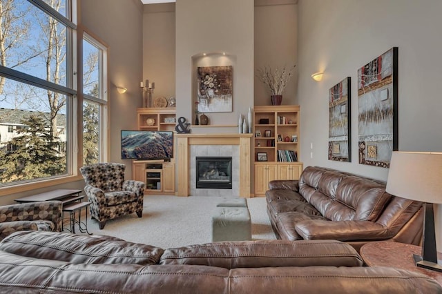 living room featuring a tile fireplace, carpet, and a towering ceiling