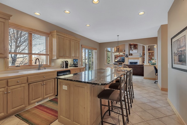 kitchen with sink, decorative columns, a center island, decorative light fixtures, and light brown cabinets