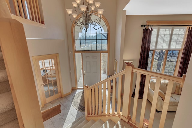 foyer featuring a towering ceiling, a wealth of natural light, a chandelier, and light tile patterned floors