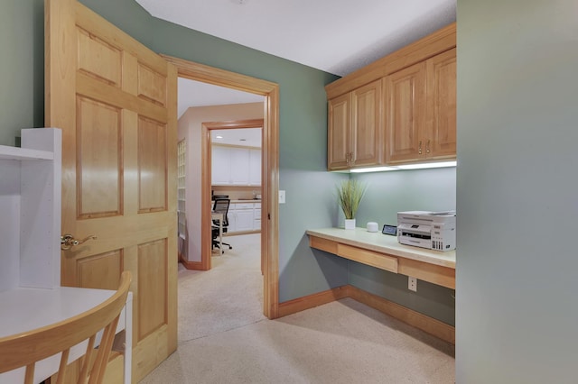 home office with light carpet and built in desk