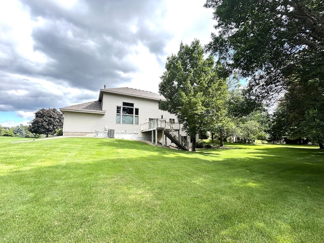 back of house with a wooden deck, a lawn, and central air condition unit