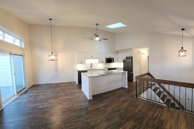 kitchen featuring white cabinetry, a center island, black refrigerator, and pendant lighting