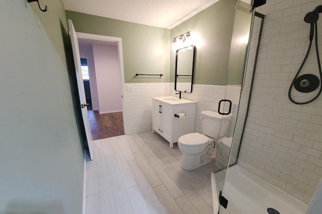 bathroom featuring tile walls, vanity, toilet, and walk in shower