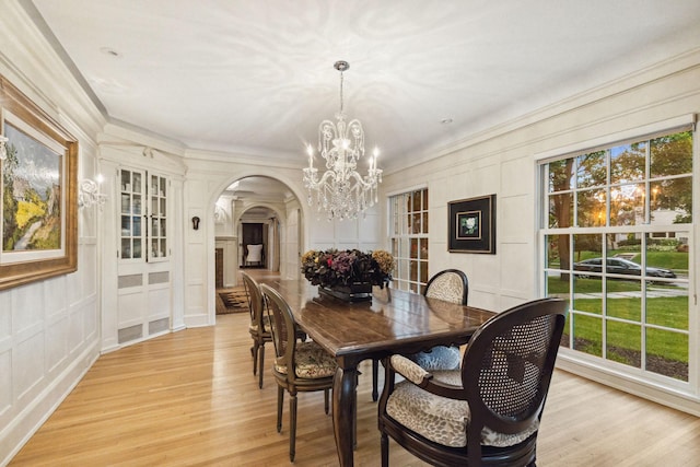 5231 Clinton Ave, Minneapolis, MN 55419 - dining area featuring crown molding, an inviting chandelier, a decorative wall, arched walkways, and light wood-style flooring