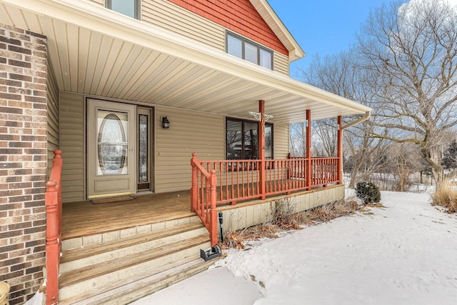 snow covered property entrance featuring covered porch