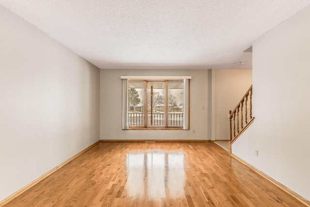 spare room with light hardwood / wood-style floors and a textured ceiling