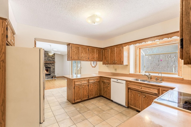 kitchen with sink, refrigerator, white dishwasher, kitchen peninsula, and a healthy amount of sunlight