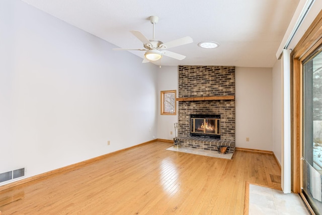 unfurnished living room featuring a brick fireplace, vaulted ceiling, light hardwood / wood-style floors, and ceiling fan