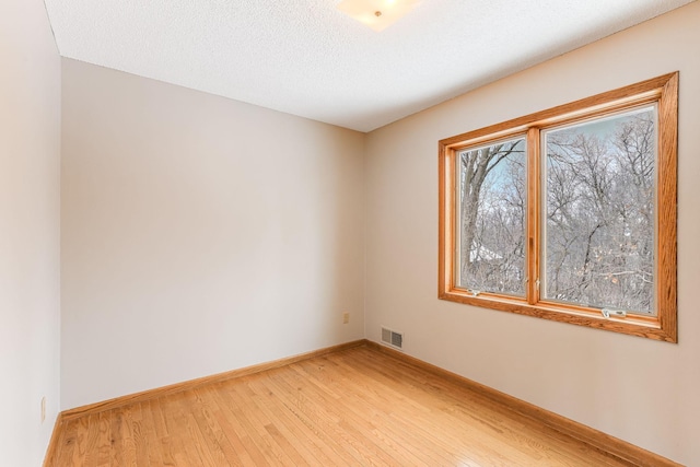 spare room featuring hardwood / wood-style flooring and a textured ceiling