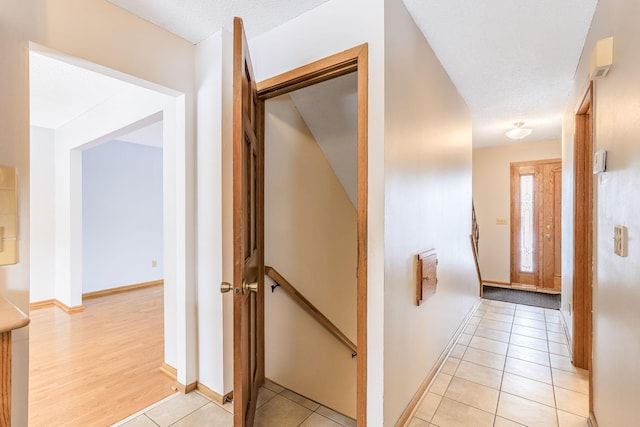 corridor featuring light tile patterned floors and a textured ceiling