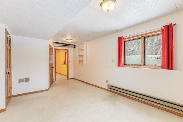 carpeted empty room featuring a baseboard heating unit and a textured ceiling