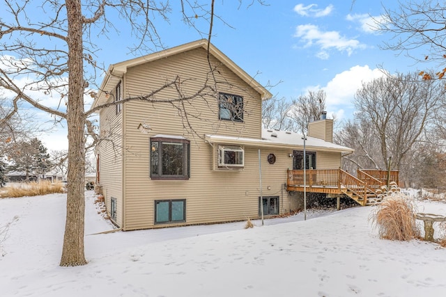 snow covered back of property featuring a wooden deck