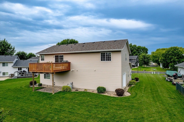 rear view of property with a wooden deck, a yard, and a garage