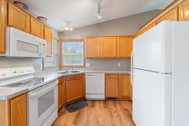 kitchen with lofted ceiling, rail lighting, sink, light wood-type flooring, and white appliances