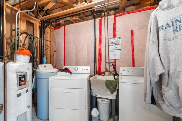 clothes washing area with separate washer and dryer, sink, and water heater