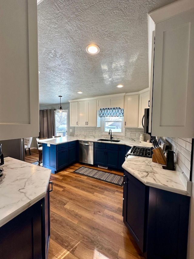 kitchen with stainless steel appliances, sink, hanging light fixtures, and white cabinets