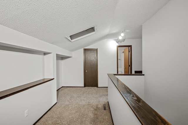 interior space with light colored carpet, vaulted ceiling, and a textured ceiling