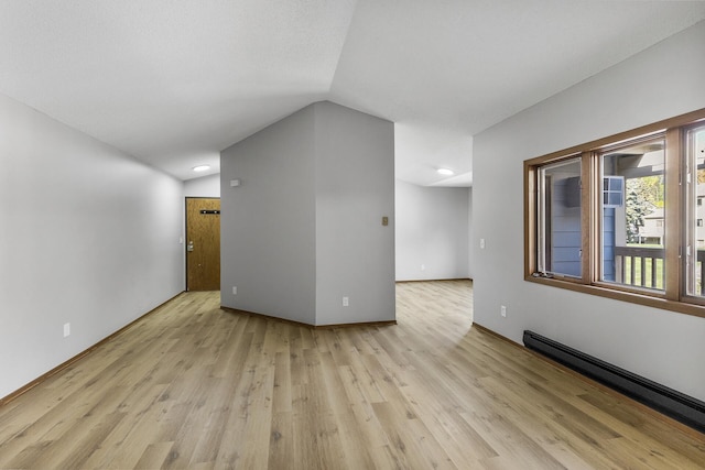 unfurnished room featuring light wood-type flooring, vaulted ceiling, and a baseboard heating unit