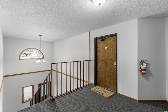 corridor with a notable chandelier, carpet floors, and a textured ceiling