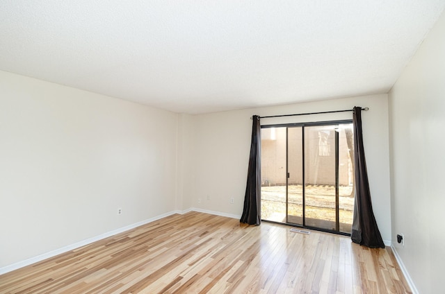 spare room featuring visible vents, baseboards, and light wood-style floors