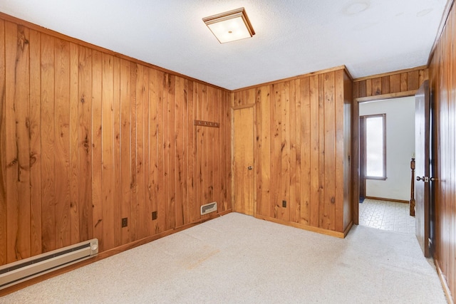 carpeted spare room with a baseboard heating unit and wooden walls