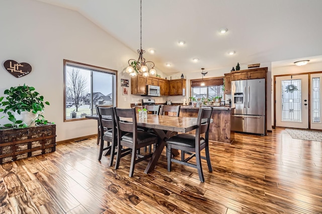 dining area with baseboards, lofted ceiling, wood finished floors, and a chandelier