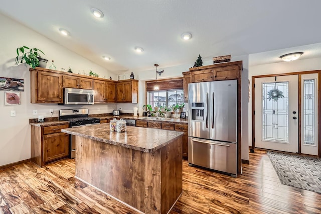 kitchen featuring a sink, dark countertops, wood finished floors, appliances with stainless steel finishes, and lofted ceiling