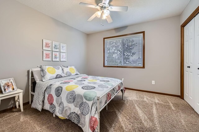 carpeted bedroom with a textured ceiling, baseboards, a closet, and ceiling fan