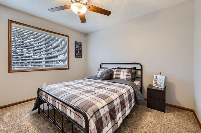 carpeted bedroom with a ceiling fan, baseboards, and a textured ceiling