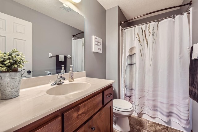 bathroom featuring visible vents, a textured ceiling, toilet, and vanity