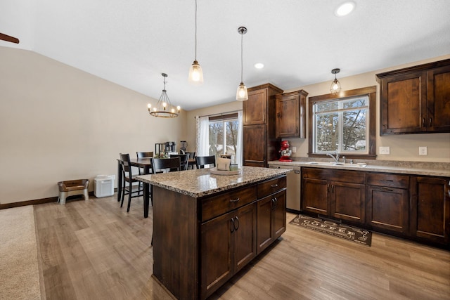 kitchen featuring hanging light fixtures, vaulted ceiling, a kitchen island, and dark brown cabinetry