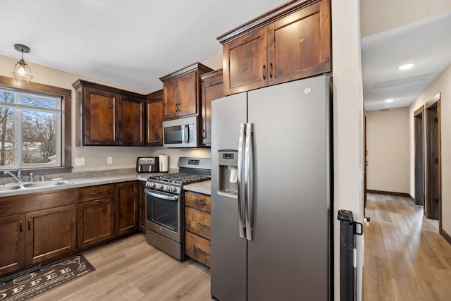 kitchen featuring dark brown cabinetry, appliances with stainless steel finishes, light hardwood / wood-style floors, and sink