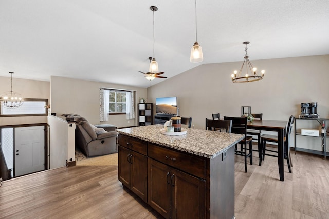 kitchen with a kitchen island, dark brown cabinets, pendant lighting, and light hardwood / wood-style flooring