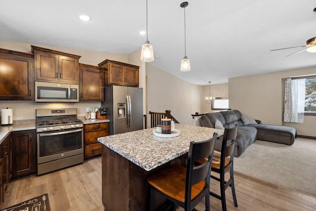 kitchen featuring lofted ceiling, a breakfast bar, hanging light fixtures, stainless steel appliances, and a center island