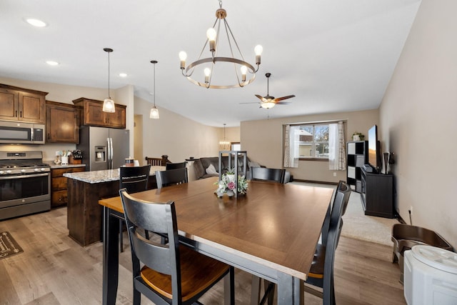 dining area featuring ceiling fan, vaulted ceiling, and light hardwood / wood-style flooring