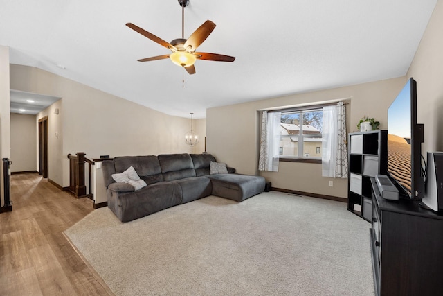 living room with lofted ceiling, ceiling fan with notable chandelier, and light hardwood / wood-style flooring