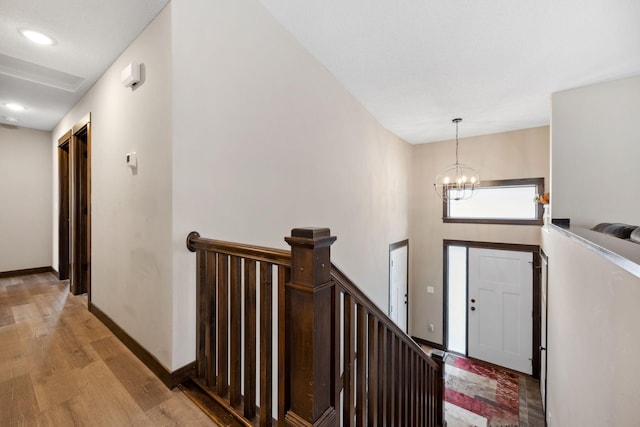 foyer entrance with an inviting chandelier, a towering ceiling, and light wood-type flooring