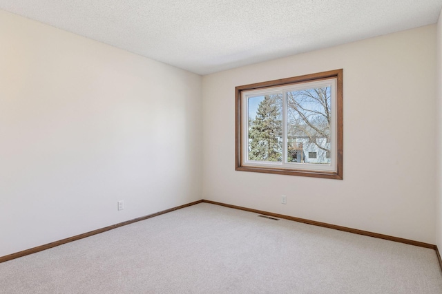 spare room with baseboards, light carpet, a textured ceiling, and visible vents