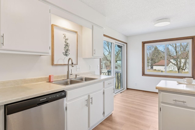 kitchen with white cabinets, dishwasher, light countertops, and a sink