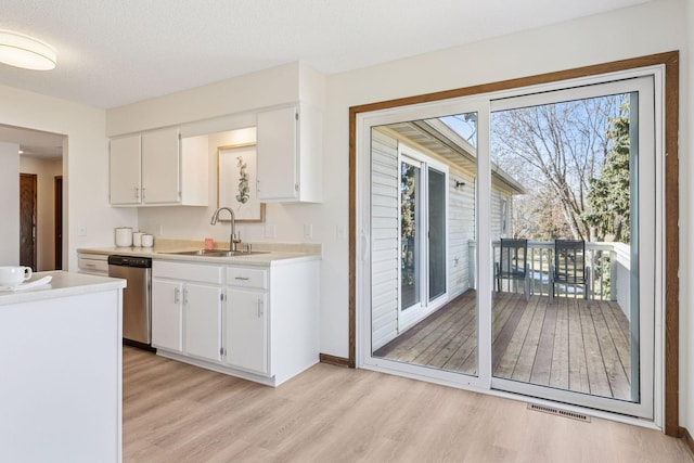 kitchen featuring stainless steel dishwasher, plenty of natural light, visible vents, and a sink