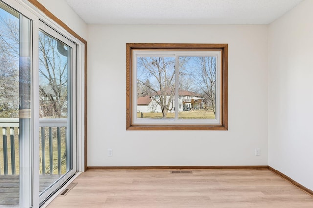 spare room featuring visible vents, baseboards, and light wood-style flooring