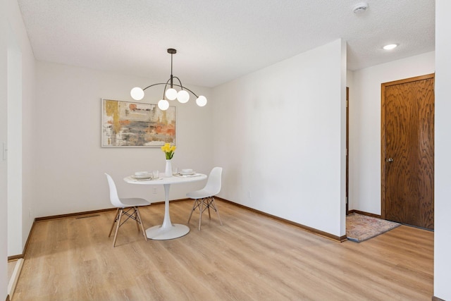 dining room with an inviting chandelier, a textured ceiling, baseboards, and wood finished floors