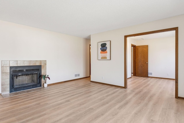 unfurnished living room featuring visible vents, baseboards, wood finished floors, and a fireplace