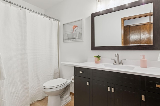 bathroom featuring a shower with shower curtain, toilet, wood finished floors, and vanity