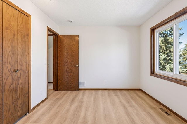 unfurnished bedroom featuring baseboards, visible vents, and light wood finished floors