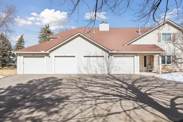 view of front facade featuring an attached garage, driveway, and a chimney