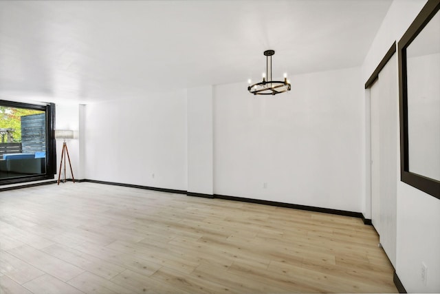 empty room featuring an inviting chandelier and light hardwood / wood-style floors