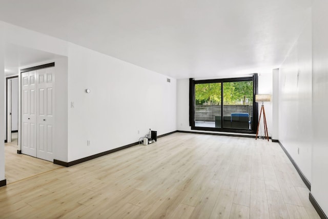 unfurnished room featuring expansive windows and light hardwood / wood-style floors