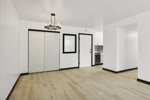 spare room with a notable chandelier and light hardwood / wood-style floors