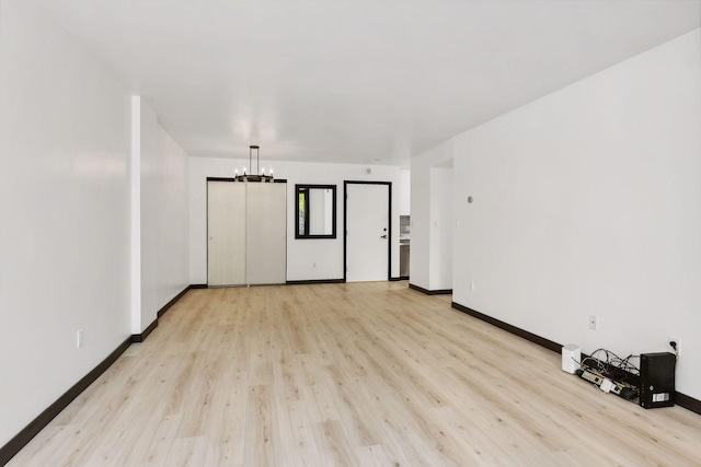 empty room featuring light wood-type flooring and a chandelier